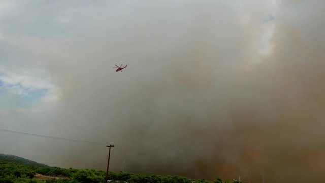 During the wildfires in Attica Greece. View of the smoke from the highway and Skycrane helicopter firefighting.