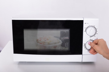 Fototapeta premium Woman Using Microwave Oven For Preparing Food
