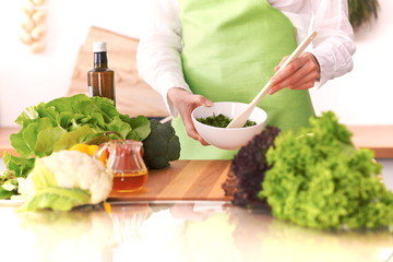 Close Up of human hands cooking vegetable salad in kitchen on the glass table with reflection. Healthy meal, and vegetarian food concept