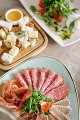 Food tray with delicious salami, pieces of sliced ham, sausage. Cutting sausage and cured meat on a celebratory table.
