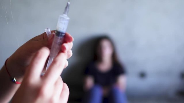 Girl is preparing a syringe with a drug for a friend