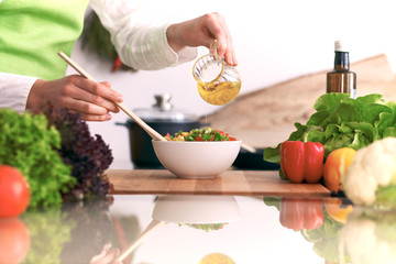 Close Up of human hands cooking vegetable salad in kitchen on the glass table with reflection. Healthy meal, and vegetarian food concept