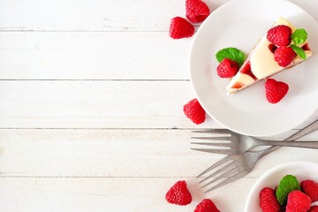 Slice of raspberry cheesecake, top view on a white wood background. Side border with copy space.