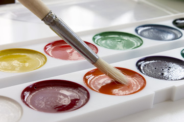Multicolored watercolor paints and brush. Office and school drawing art design