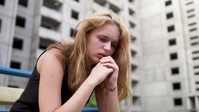 Nervous girl is sitting near high building