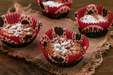 Cookies with oatmeal and cottage cheese in paper forms on a piece of fabric on a wooden background.