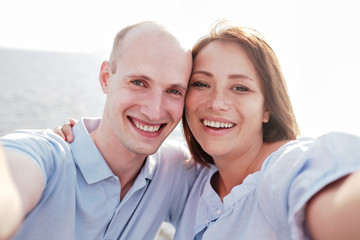 Self portrait of young, caucasian couple in shirts making selfie with his wonderful woman on mobile phone