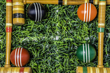 green grass framed with wooden croquet mallets and balls with room for copy in the middle