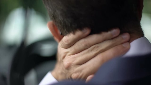 Tired man in suit feeling neck discomfort, driving car, sedentary lifestyle