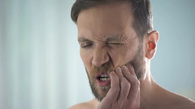 Male suffering from tooth ache, strong dental pain, pulp inflammation, decay