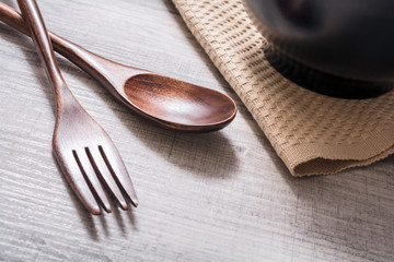 Wooden Set Of Fork And Knife Next To A Bowl With Napkin On A Table, High Angle View