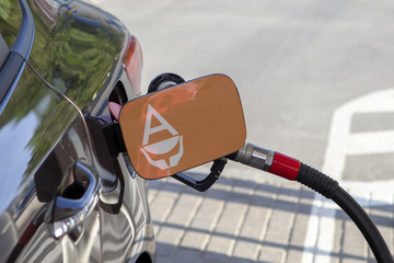 Fueling car with petrol pump at a gas station.
