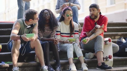 Group of hungry students having lunch sitting on stairs.