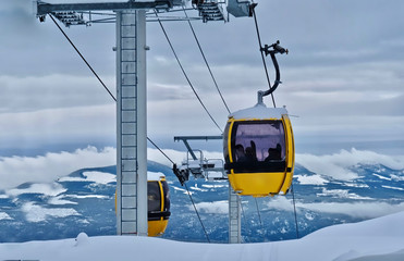 Fototapeta na wymiar Gondola at ski resort. Chair lift with view of snowy mountains. Beautiful winter day at Big White Ski Resort. Kelowna. British Columbia. Canada.