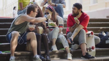 Group of hungry students having lunch sitting on stairs.