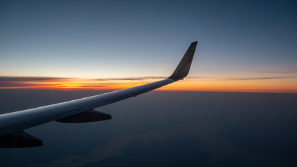 Right Wing of Airplane In Mid Air with Sunrise in the background