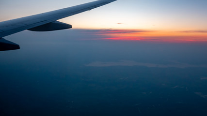 Fototapeta premium Partial View of Airplane Wing with Colorful Sunrise in the horizon