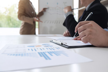 Business woman leader making presentation with her colleagues, pointing to the graph on board and business strategy during meeting in modern office