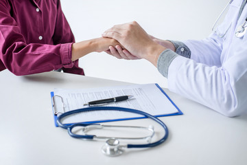 Doctor touching patient hand for encouragement and empathy on the hospital, cheering and support patient, medical examination, trust and ethics