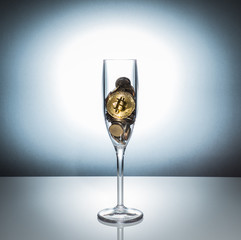 A view of bitcoin in champagne glass among other coin with white background.