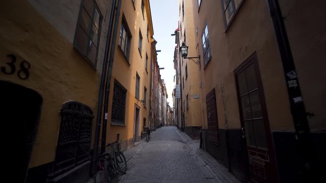Historical alley in the Old Town of Stockholm Sweden. A steady glide cam footage moving backwards. Early morning in Gamla Stan, empty streets with no tourists around. A narrow historical alley.