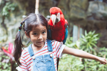Cute asian child girl with beautiful macaw parrot in her shoulder in the zoo © pingpao