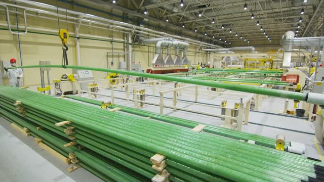 Workers Control Green Pipe Lifting With Crane Hook In Modern Workshop