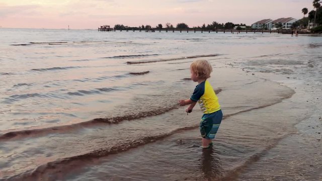 Young toddler boy playing on the beach at sunset. High Definition 1920 x 1080 60fps footage. Lapping waves while young boy plays in the water and with the sand.
1920 x 1080 60fps
