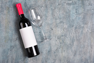 Flat lay of lying red wine bottle with white empty label and glass for tasting