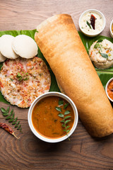 Group of South Indian food like Masala Dosa, Uttapam, Idli/idly, Wada/vada, sambar, appam, semolina halwa, upma served over banana leaf with colourful chutneys, selective focus
