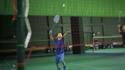 Asian boy playing badminton. - obrazy, fototapety, plakaty