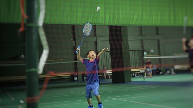 Asian boy playing badminton.