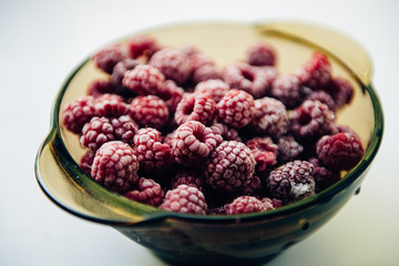 Frozen raspberries on a plate on white background lifestyle