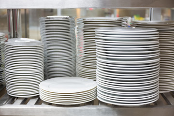 White ceramic dinnerware on restaurant stainless shelves.