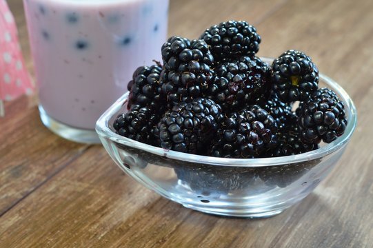 Close-up of  juicy blackberries in a bowl on rustic table and milk and berry milkshake
