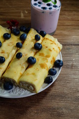 Pancake rolls, roast without fat, wraped with white cheese. They were sprinkled with blueberries. Blueberry cocktail with fresh blueberries
