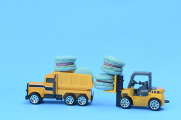 mini macaroons with car toys on blue color backgrounds