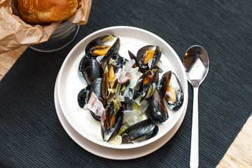 Mussels with onions and bacon in cream sauce in deep plate