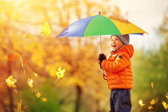 Child standing with umbrella in beautiful autumnal day