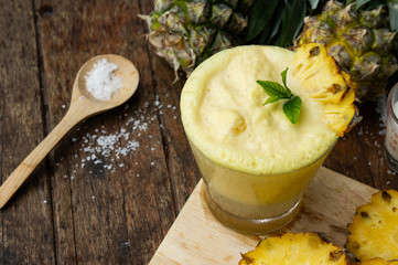 Pineapple juice and pineapple slices cut into pieces on a wooden table. Healthy wood fiber helps to reduce food. Pineapple juice Contains fresh milk, nectar and salt.