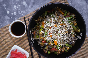 Buckwheat noodles with meat and vegetables, Asian wok on a gray