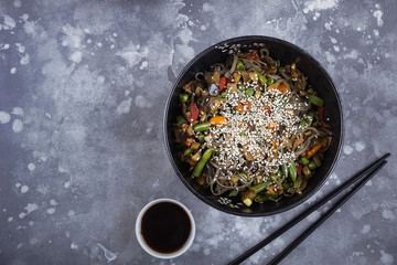 Buckwheat noodles with meat and vegetables, Asian wok on a gray
