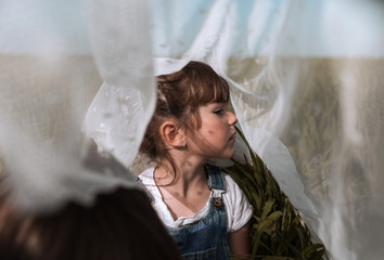 Thoughtful girl sitting under mesh netting outdoors