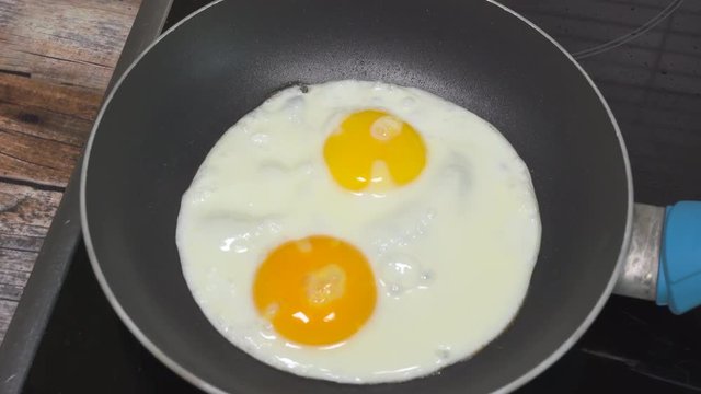 Cooking sunny side up eggs for breakfast. Close up slider shot.