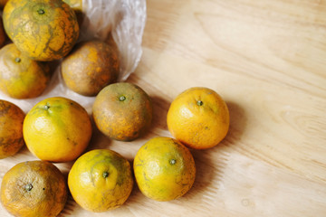 Fresh oranges fruits a transparen plastic bag on wooden background.