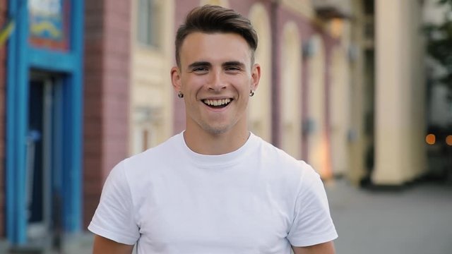 Closeup portrait young man looking smiling at camera, european building background