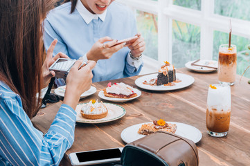 women talking and take a photo dessert and food in cafe restaurant, enjoy eating