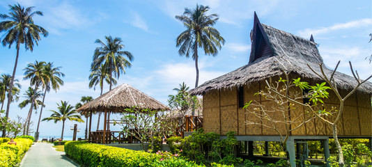 Traditional beach bungalows and coconut palms on Koh Phi Phi island, Thailand. Panorama - obrazy, fototapety, plakaty