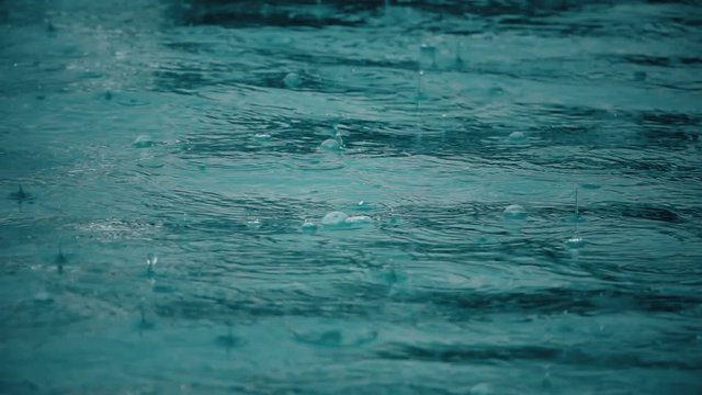 Slow motion shot of rain drops and bubbles on sea surface
