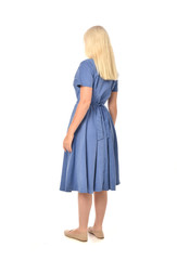full length portrait of blonde girl wearing blue dress. standing pose with back to the camera. isolated on white  studio background.